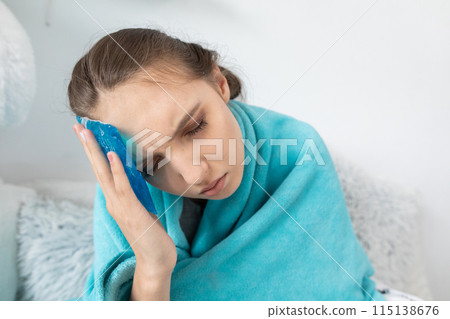 The teenager puts cold compresses on her head to reduce the high temperature. The teenager puts cold compresses on her head to reduce the high temperature. 115138676
