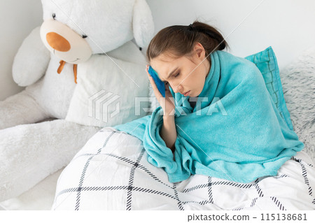 The teenager puts cold compresses on her head to reduce the high temperature. The teenager puts cold compresses on her head to reduce the high temperature. 115138681