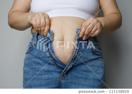 Woman trying to zip up her jeans pants, dieting concept 115138929