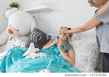 Mom touches her daughter's forehead with her hand, checking if the high temperature still persists. Mom touches her daughter's forehead with her hand, checking if the high temperature still persists. 115139160