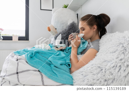 A cold teenager snot tears his nose in a handkerchief all the time under a warm duvet. A cold teenager snot tears his nose in a handkerchief all the time under a warm duvet. 115139189