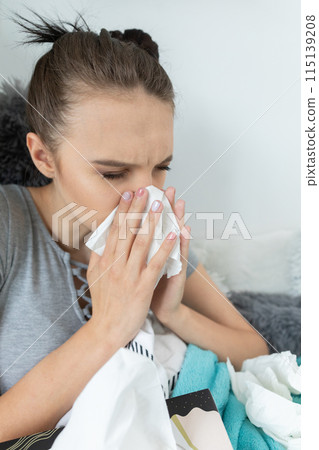 A cold teenager snot tears his nose in a handkerchief all the time under a warm duvet. 115139208