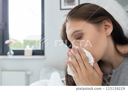 A cold teenager snot tears his nose in a handkerchief all the time under a warm duvet. A cold teenager snot tears his nose in a handkerchief all the time under a warm duvet. 115139229