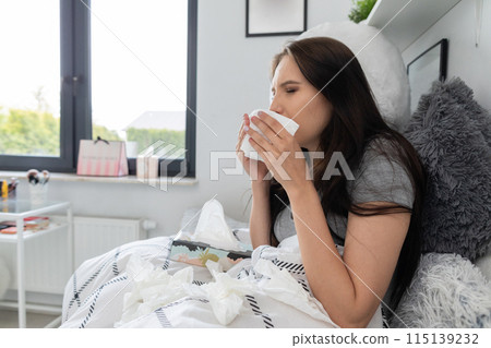 Very sick teenager lies in bed and groats in a handkerchief. 115139232
