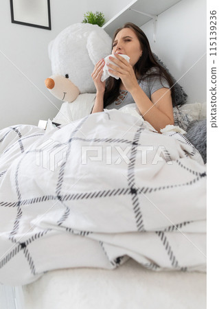 Very sick teenager lies in bed and groats in a handkerchief. 115139236