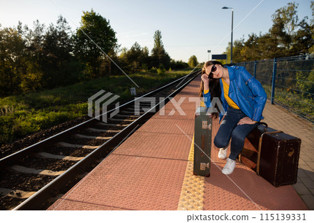 A bored teenager waits on a train station for a train that is very delayed on her summer vacation in southern Europe. 115139331