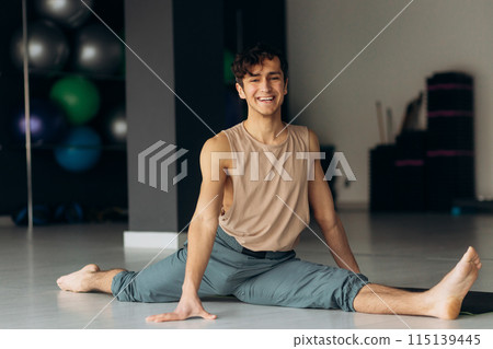 Fit guy does front leg split workout exercise in studio. Handsome man trains at home. Sports lifestyle 115139445