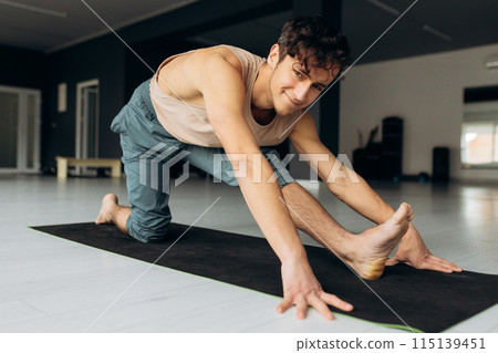 Happy athletic young man stretching his body. Guy enjoying yoga practice, side view. Healthy lifestyle concept Happy athletic young man stretching his body. Guy enjoying yoga practice, side view. Healthy lifestyle concept 115139451