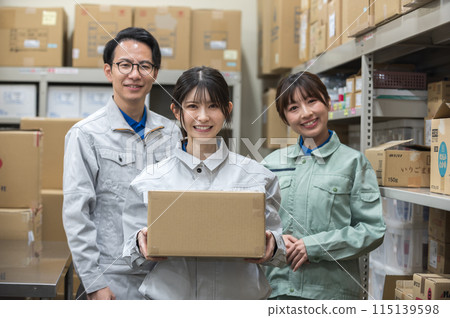 A woman in work clothes holding cardboard and male and female workers 115139598