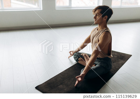 Side view of handsome calm focused guy sitting on floor meditating relaxation. Yoga man concept Side view of handsome calm focused guy sitting on floor meditating relaxation. Yoga man concept 115139629