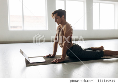 Handsome young man practicing fitness with online training on laptop 115139635