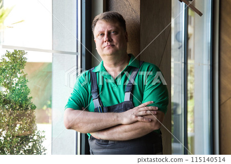 Working man in green T-shirt and blue overalls Working man in green T-shirt and blue overalls 115140514