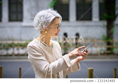 操作智慧型手機的典雅的資深婦女 115141485