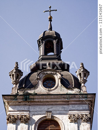 Baroque Bell Tower. Upper section of a church with a bell tower, clear sky above, symbolizing historical religious architecture. Baroque Bell Tower. Upper section of a church with a bell tower, clear sky above, symbolizing historical religious architecture. 115141667