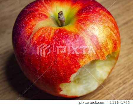 Freshly Bitten Apple. A red apple with a bite taken out, resting on a wooden surface, evoking themes of health and freshness. Freshly Bitten Apple. A red apple with a bite taken out, resting on a wooden surface, evoking themes of health and freshness. 115141735