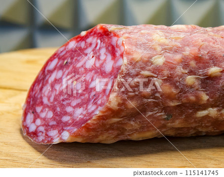 Salami with visible fat marbling, suggesting a gourmet or deli setting, ready to be sliced. 115141745