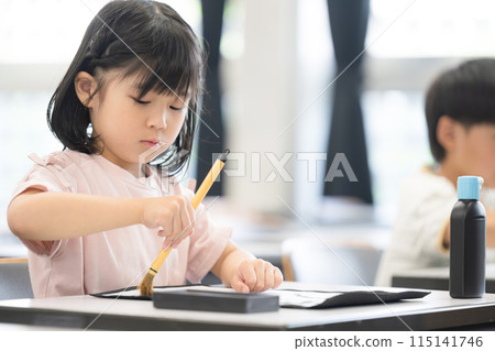 An elementary school girl learning calligraphy in a bright elementary school classroom 115141746