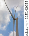 A modern wind turbine stands tall under a blue sky with fluffy clouds in the background 115142055