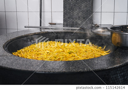 yellow carrots are stewed in cauldron for cooking Asian Uzbek pilaf in kitchen in Tashkent in Uzbekistan yellow carrots are stewed in cauldron for cooking Asian Uzbek pilaf in kitchen in Tashkent in Uzbekistan 115142614