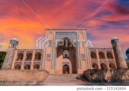 facade of ancient Uzbek Islamic Kukeldash madrassah in Tashkent in Uzbekistan. Old stone medieval oriental madrasah in Asia at sunset 115142684
