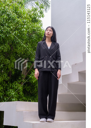 Full length portrait of a professional woman in business attire on modern architectural steps 115143125