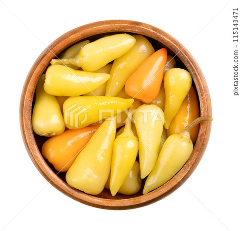 Pickled yellow hot baby peppers, in a wooden bowl. Small hot chilis, pepperonis, or Capsicum pepper, pasteurized and preserved in a vinegar brine and salt. Close-up, from above, isolated, food photo. 115143471