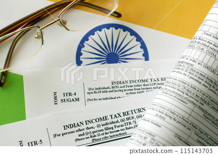 Indian income tax return blank form with pen and indian rupees bills on indian country flag close up. Annual tax report concept Indian income tax return blank form with pen and indian rupees bills on indian country flag close up. Annual tax report concept 115143703