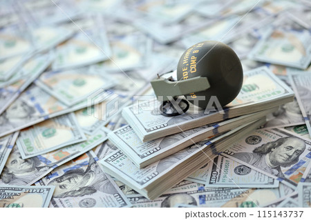 Grenade with a check against the background of huge amount of american dollar bills close up 115143737