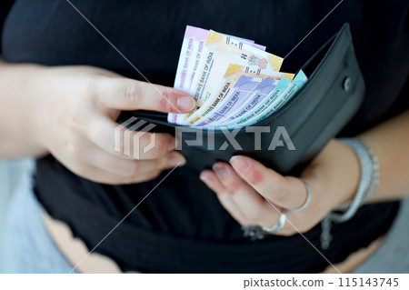 Woman hand with indian rupees bills close up. Concept of financial operations in cash in India Woman hand with indian rupees bills close up. Concept of financial operations in cash in India 115143745