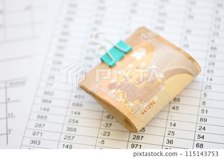 Heap of euro money bills in stationery clip on papers with calculations and receipts close up. Business and accounting concept 115143753
