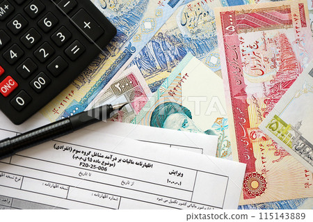 Iranian annual income tax return form F20-25-006 ready to fill on table with pen, calculator and iranian money close up 115143889