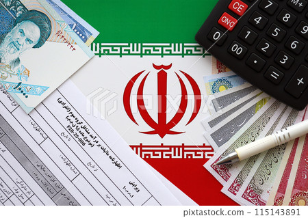 Iranian annual income tax return form F20-25-006 ready to fill on table with pen, calculator and iranian money on flag close up Iranian annual income tax return form F20-25-006 ready to fill on table with pen, calculator and iranian money on flag close up 115143891