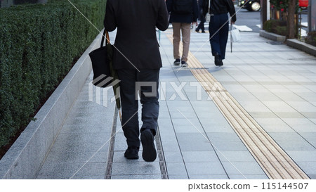 Businessman walking on a downtown road in the evening 115144507