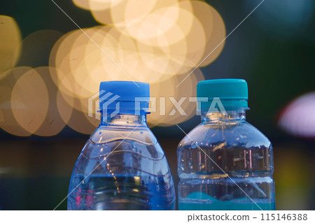 Two clear plastic water bottles with blue caps 115146388