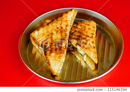 a golden brown grilled cheese sandwich on a rectangular metal plate. a golden brown grilled cheese sandwich on a rectangular metal plate. 115146394