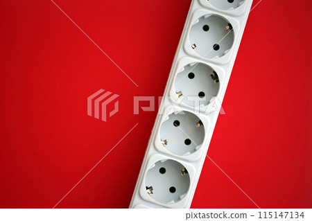 White electrical multi plug extender with european socket on bright red background close up 115147134