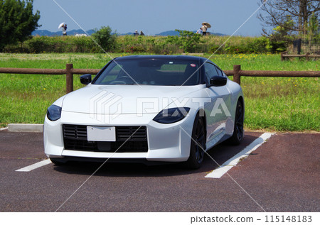 An image of a person going for a drive in a white Japanese sports car on a sunny day off, taking a break in a parking lot in a park and admiring the scenery. An image of a person going for a drive in a white Japanese sports car on a sunny day off, taking a break in a parking lot in a park and admiring the scenery. 115148183