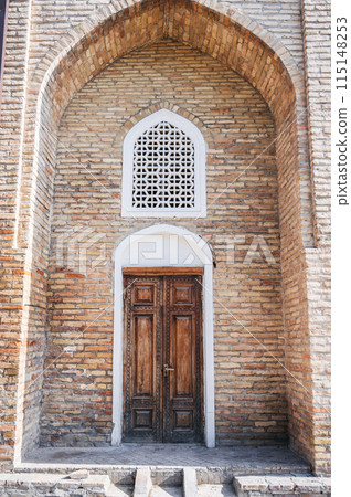 carved wooden door with oriental Uzbek pattern in brick wall with arch in Barak-Khan Madrasah in Tashkent in Uzbekistan carved wooden door with oriental Uzbek pattern in brick wall with arch in Barak-Khan Madrasah in Tashkent in Uzbekistan 115148253