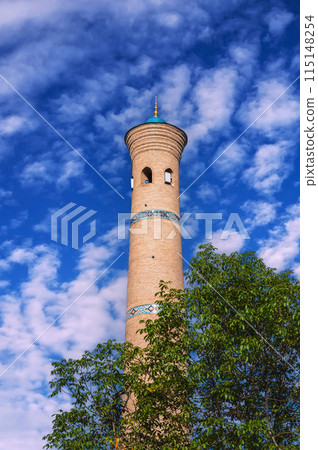 ancient old minaret of Khast Imom mosque on background at blue sky in summer. Islamic complex Hazrati Imam in Tashkent in Uzbekistan ancient old minaret of Khast Imom mosque on background at blue sky in summer. Islamic complex Hazrati Imam in Tashkent in Uzbekistan 115148254