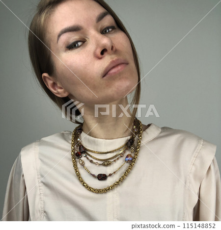 Portrait of a young woman in unusual massive necklace 115148852