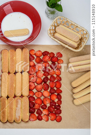 Soak the savoiardi in milk and arrange in rows on top of the strawberries. 115148910