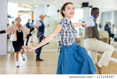 Cheerful female practicing lindy hop in pair with man Cheerful female practicing lindy hop in pair with man 115149597