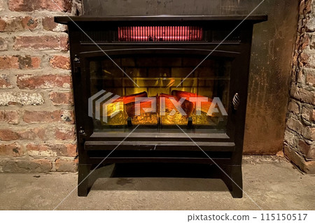 Fireplace with burning firewood in the interior of a restaurant. A cozy scene with a crackling fireplace set against a rustic brick wall, radiating warmth and comfort. 115150517