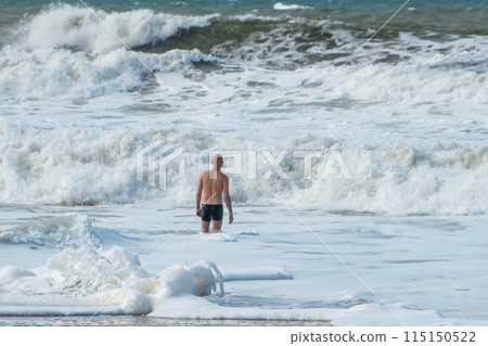 A man alone swims in the Atlantic Ocean in a storm, big waves, danger on the beach A man alone swims in the Atlantic Ocean in a storm, big waves, danger on the beach 115150522