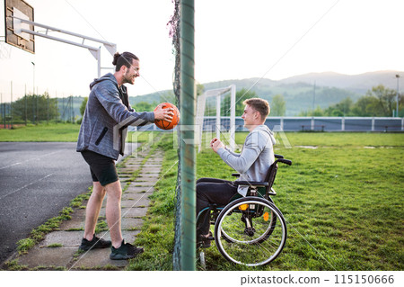 Disabled young man feeling excluded, want to play basketball with his friends, but because of wheelchair he can't. Disabled young man feeling excluded, want to play basketball with his friends, but because of wheelchair he can't. 115150666