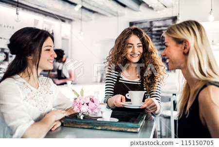 Barista working in coffee shop, serving customers. University student working part-time in cafe. Barista working in coffee shop, serving customers. University student working part-time in cafe. 115150705