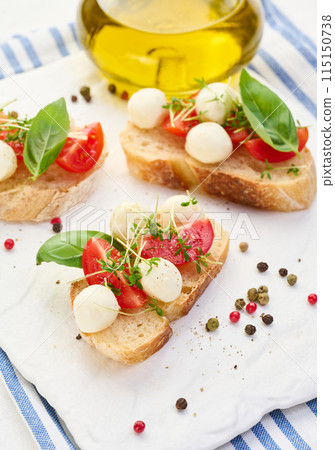 Round mozzarella, cherry tomatoes and microgreens on a piece of white bread, a healthy sandwich 115150738