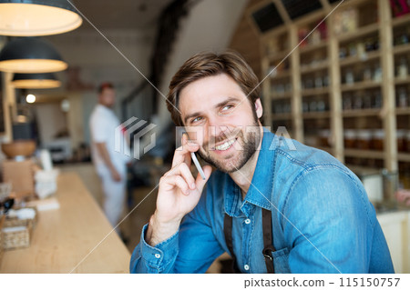 Man in small business, working in his bistro, phone calling to supplier. Young male business owner. Man in small business, working in his bistro, phone calling to supplier. Young male business owner. 115150757