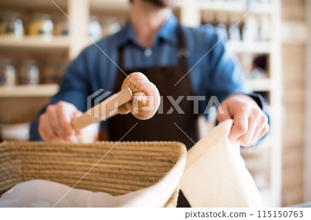 Handsome man working in package-free store using reusable containers. Zero waste shops offering package-free bulk goods and sustainable alternatives. Handsome man working in package-free store using reusable containers. Zero waste shops offering package-free bulk goods and sustainable alternatives. 115150763