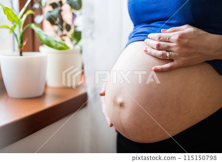 Unrecognizable pregnant woman touching her naked belly. Unrecognizable pregnant woman touching her naked belly. 115150798